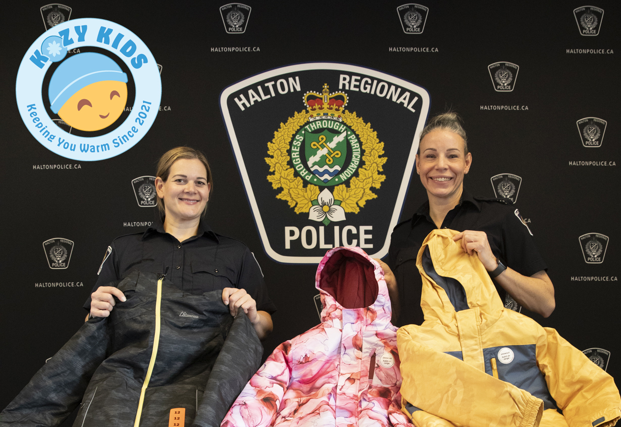 Two HRPS Constables displaying donated snow suits and the Kozy Kids logo in the top left corner.